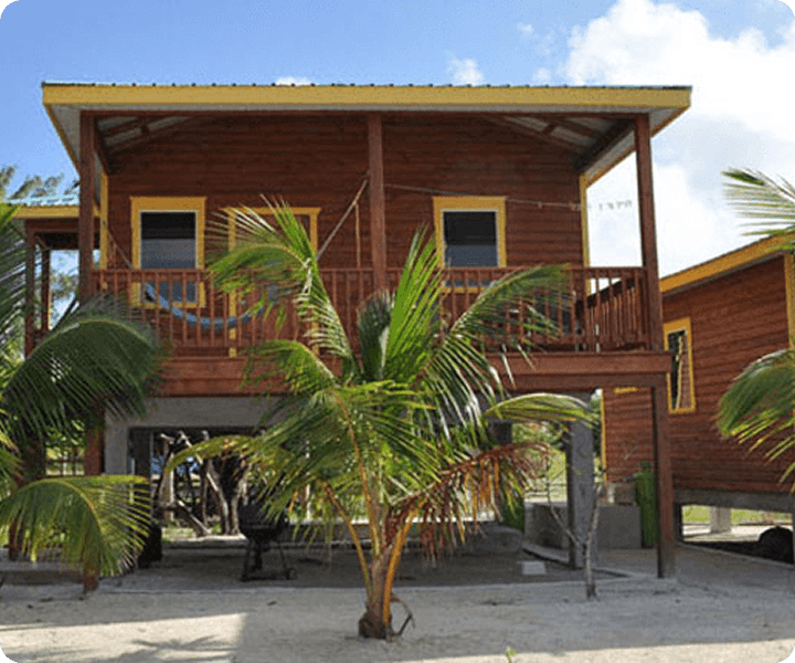 Wooden beach house with palm trees.