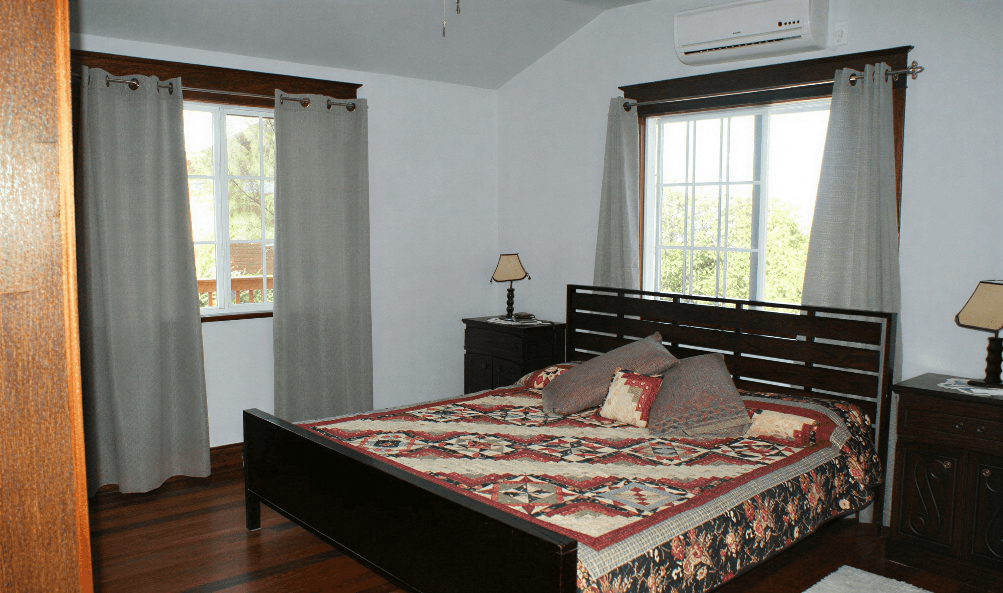 Cozy bedroom with wooden bed and windows.
