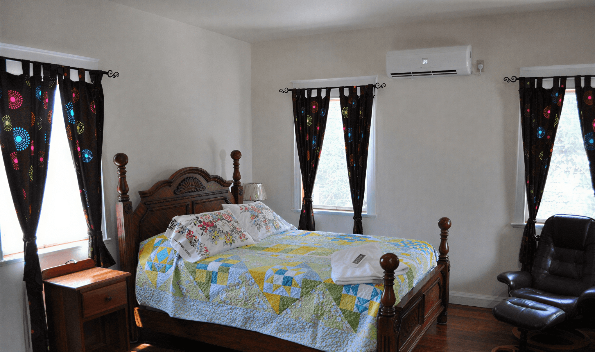 Bedroom with bed, curtains, and armchair.