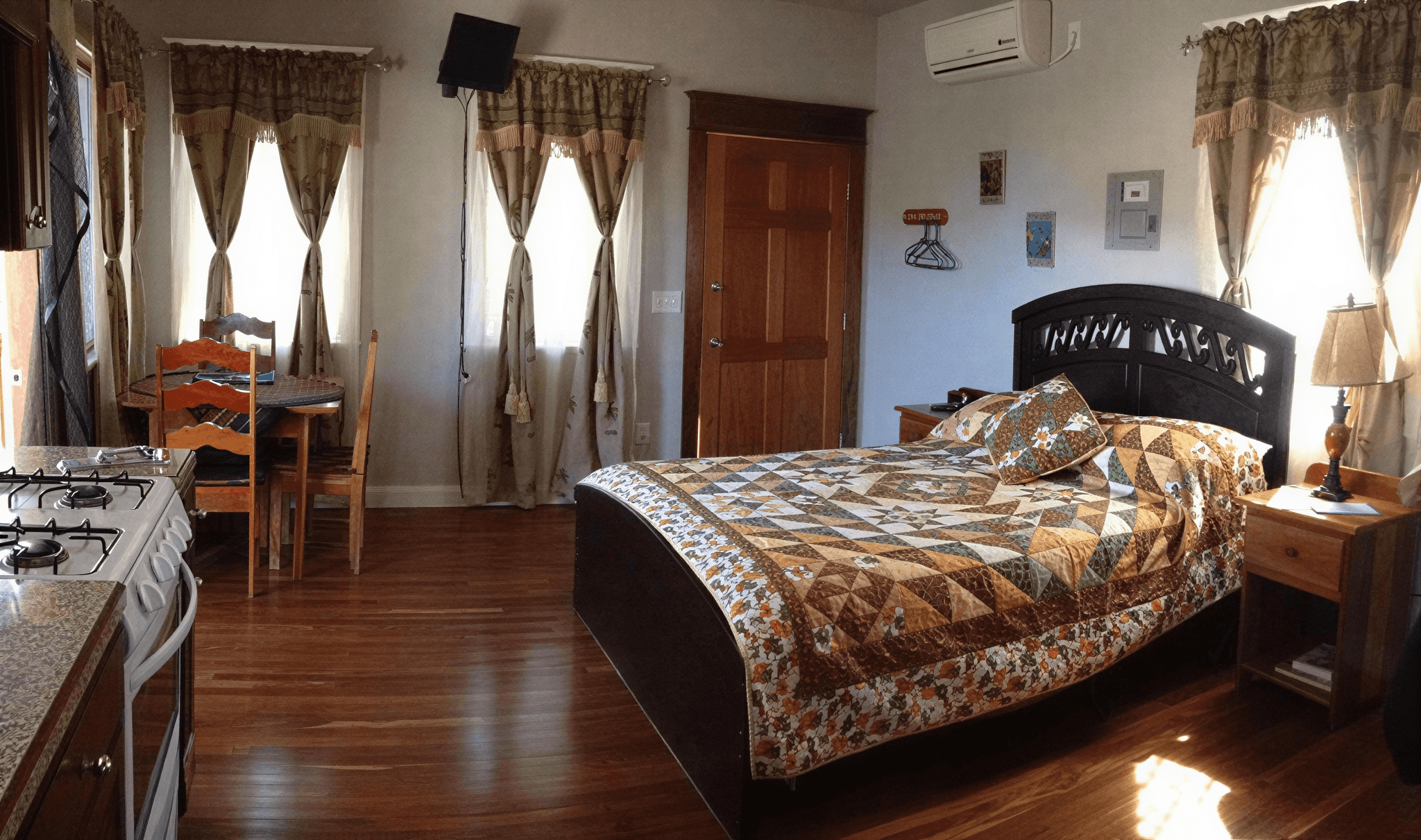 Cozy bedroom with patterned quilt and curtains.