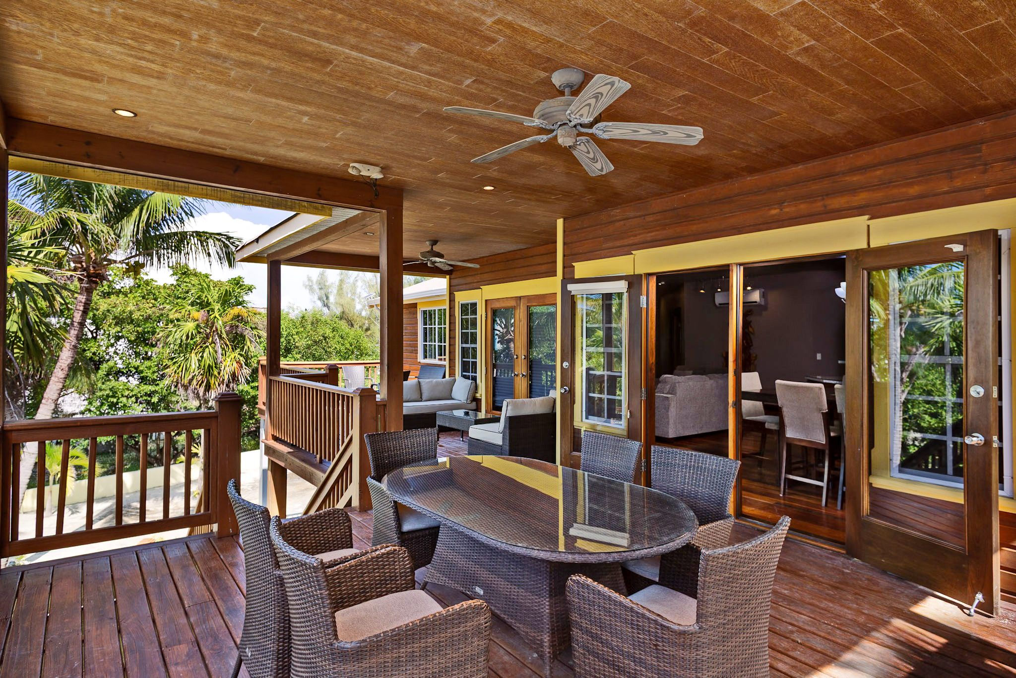 Wooden patio with wicker furniture and fan.