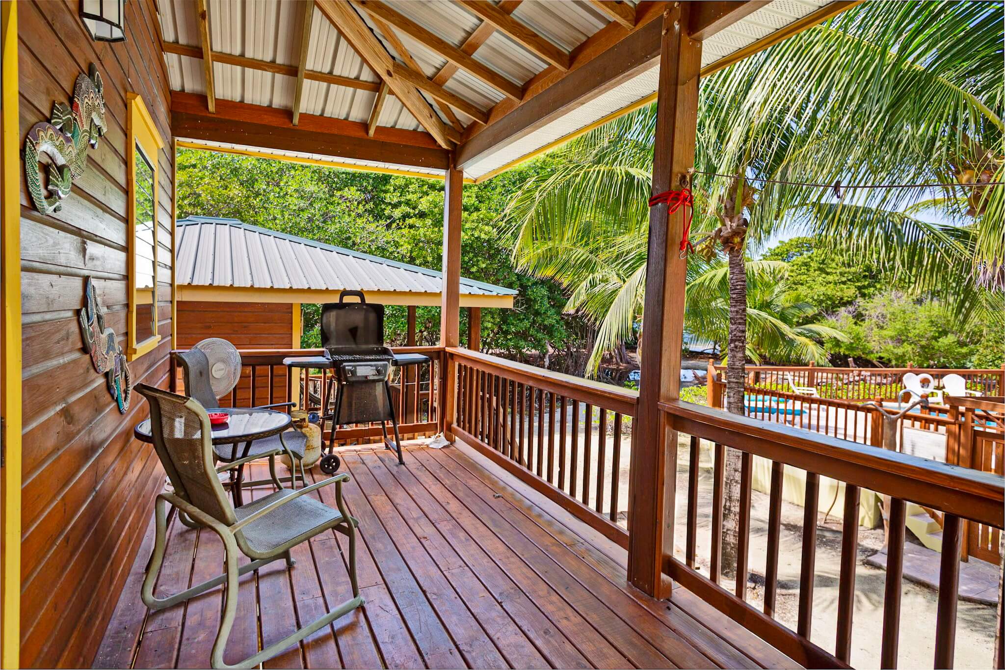 Wooden porch with chairs and tropical view.