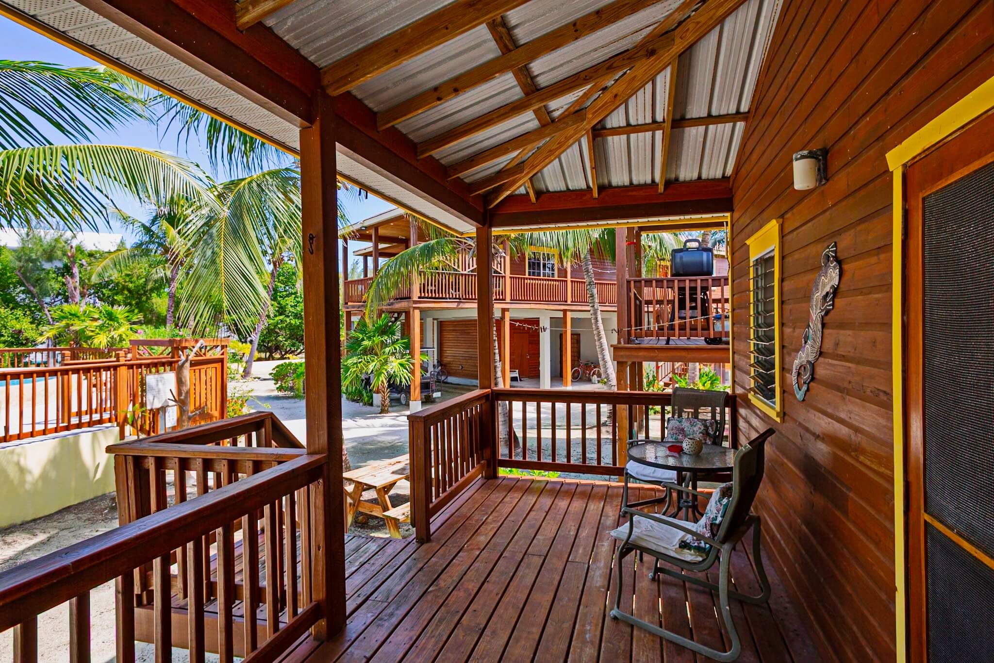 Wooden porch with chairs and tropical view.
