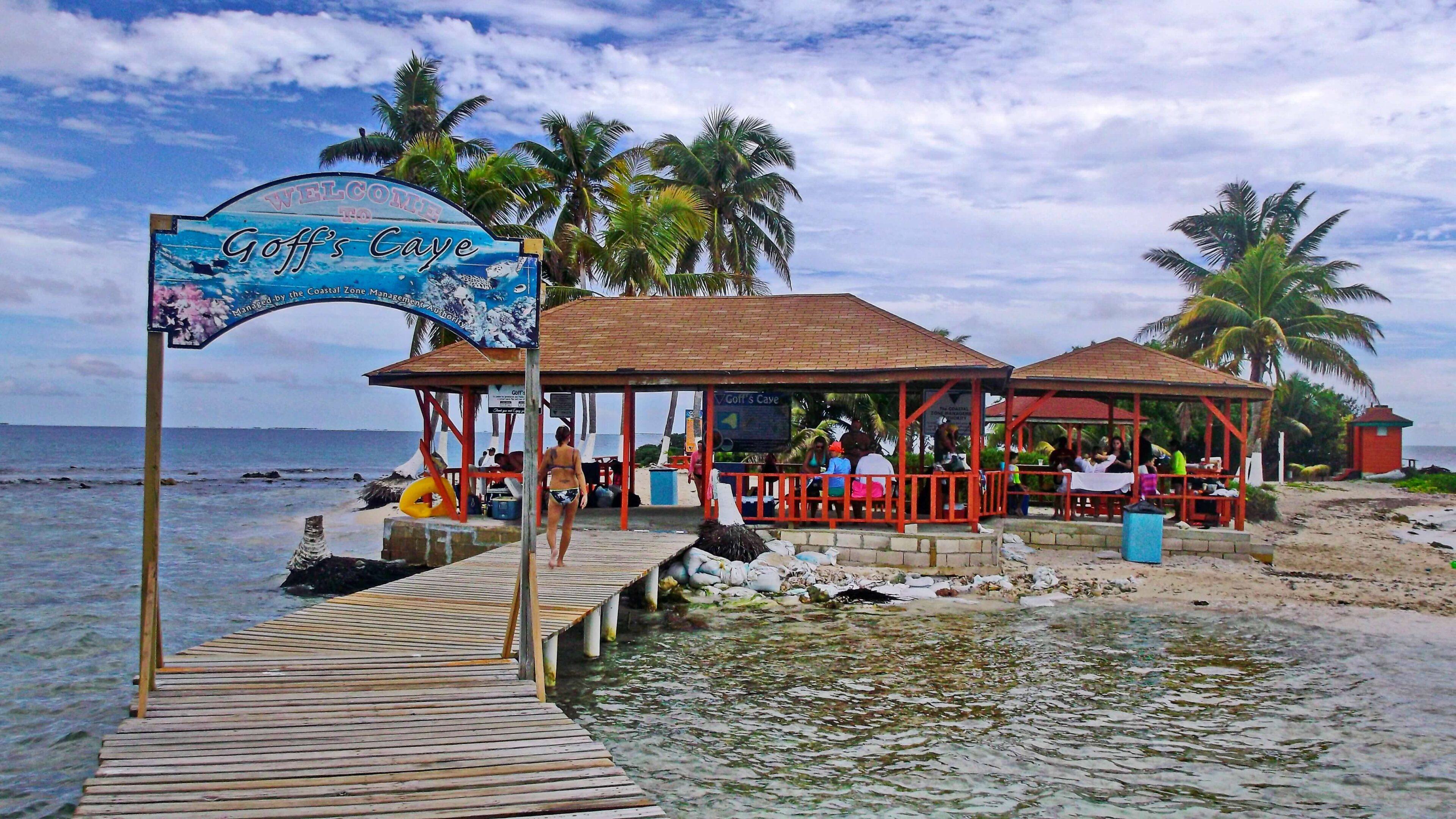 Beachside cafe with palm trees and pier.