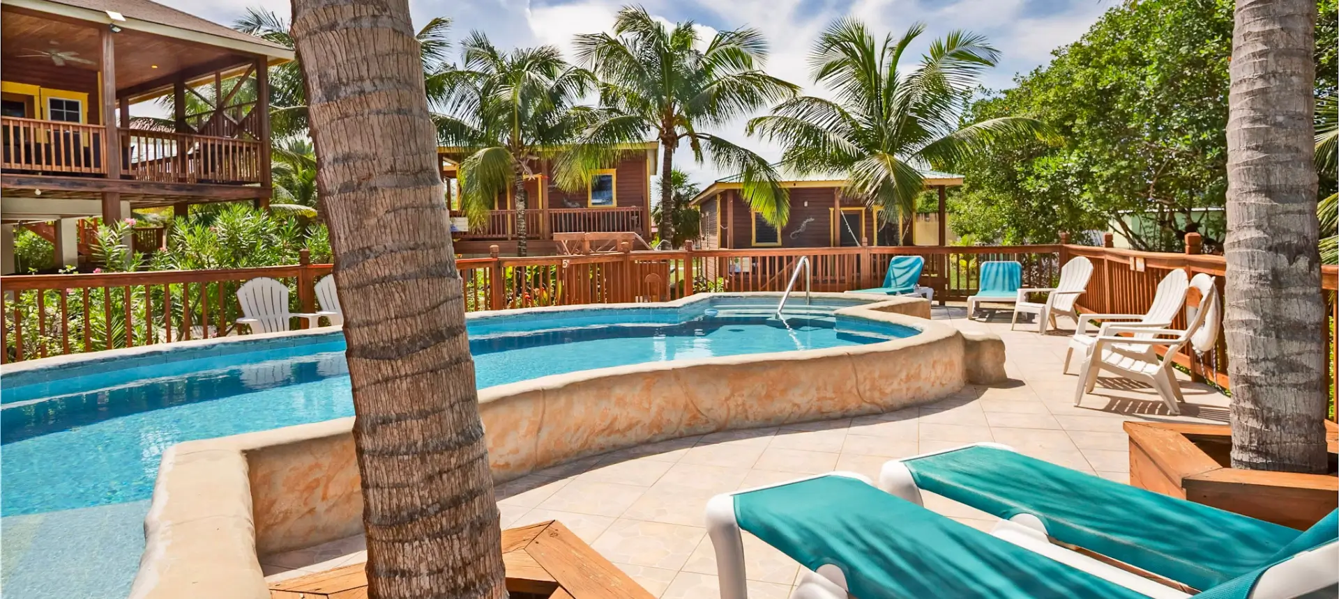 Tropical poolside with loungers and palm trees.