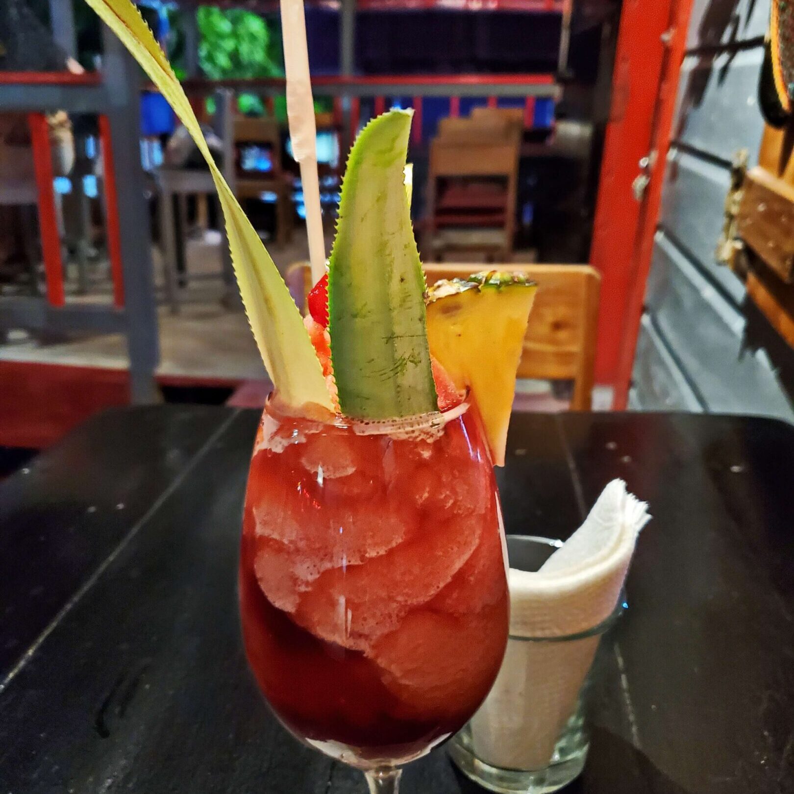 Colorful cocktail with fruit garnish on table.